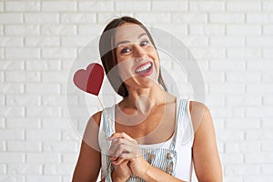Happy beautiful woman holding red paper heart