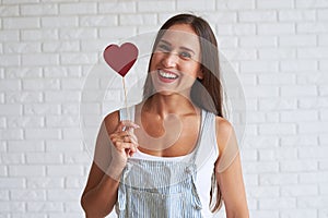 Happy beautiful woman holding red paper heart near of her face