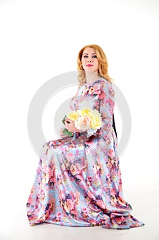 Happy beautiful woman with long blond curly hair posing with flowers in studio on white background