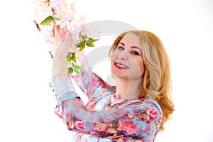 Happy beautiful woman with long blond curly hair posing with flowers in studio on white background