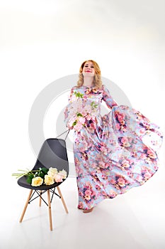 Happy beautiful woman with long blond curly hair posing with flowers in studio on white background