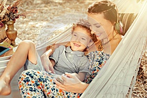 Happy beautiful woman lying in hammock with her son