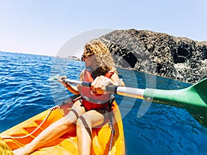 Happy beautiful woman in outdoor leisure activity doing kayak trip at the ocean - enjoying summer holiday vacation with sport