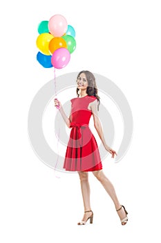 Happy beautiful woman in red dress holding colorful balloons