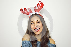 Happy beautiful woman with reindeer horns on her head looks at camera on white background. Christmas holidays.