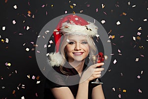 Happy beautiful woman Santa with falling confetti on black background. Christmas holiday and New Year party portrait