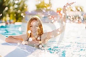 A happy beautiful woman in splashes of water by the side of a pool.