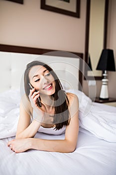 Happy beautiful woman talking on the phone at home in the morning