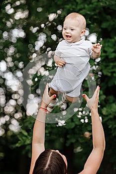Happy beautiful woman, young mother playing and throwing up with her adorable baby son, cute little boy, enjoying