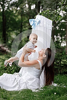 Happy beautiful woman, young mother playing and throwing up with her adorable baby son, cute little boy, enjoying