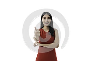 Happy beautiful young Asian woman in casual business red dress is smiling, showing thumbs up while looking at camera, isolated