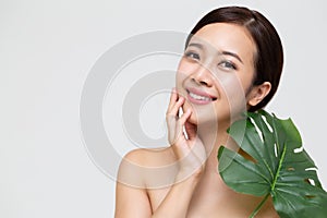 Happy beautiful young Asian woman with clean fresh skin and green leaves.