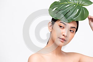 Happy beautiful young Asian woman with clean fresh skin and green leaves concept Girl beauty face care.