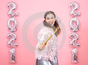 Young woman on a pink background with silver ballons in the form of the numbers 2021 photo