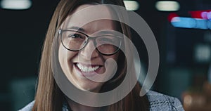 Happy beautiful young Caucasian boss, leader business woman in eyeglasses smiling at camera in blurry office background.