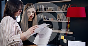 Happy beautiful young Caucasian business coach woman talking to middle aged colleague at trendy loft coworking office.