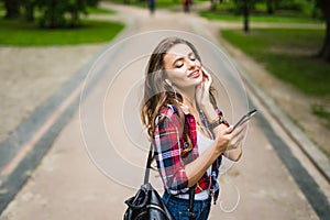 Happy beautiful young caucasian girl with green smart phone outdoors on sunny