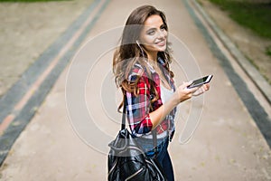 Happy beautiful young caucasian high school girl with green smart phone outdoors on sunny