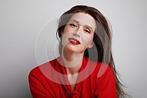 Happy and beautiful young caucasian woman wearing red top and red lipstick. Posing over white background.