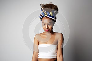 Happy beautiful young female with Afro curly hairstyle, posing aside with cheerful expression, isolated over bright