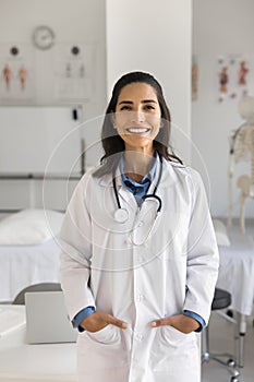 Happy beautiful young Hispanic doctor woman standing in medical office