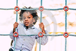 Happy and beautiful young kid black race african with ethnic alternative hair playing in a playground with coloured cords and have