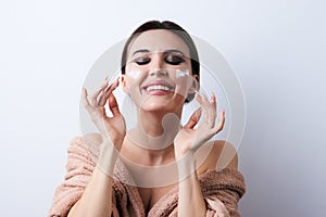 Happy beautiful young woman applying cream at her face, close-up