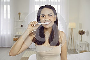 Happy beautiful young woman cleaning her teeth with whitening toothpaste in the morning