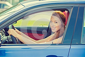 Happy beautiful young woman driving her new blue car