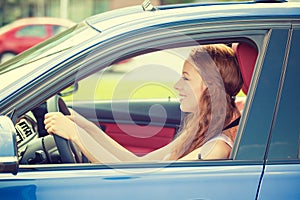 Happy beautiful young woman driving her new blue car