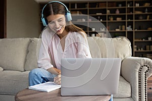 Happy beautiful young woman in headphones listening educational lecture.