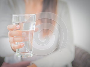 Happy beautiful young woman holding drinking water glass in her hand.