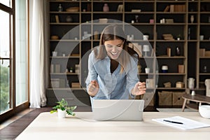 Happy beautiful young woman laughing looking at computer screen.