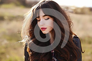 Happy beautiful young woman with long black healthy hair enjoy fresh air and sun light outdoor at sunset.