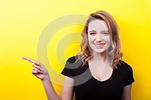 Happy beautiful young woman pointing on the side