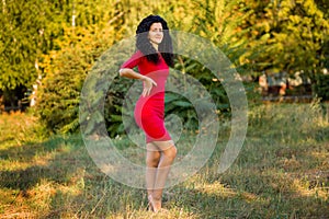 Happy beautiful young woman in red dress relax in summer park. Freedom concept