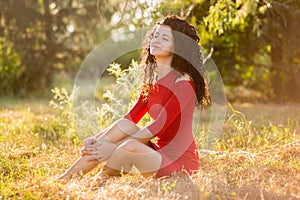 Happy beautiful young woman in red dress relax in summer park. Freedom concept