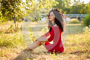 Happy beautiful young woman in red dress relax in summer park. Freedom concept