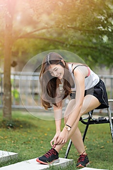 Happy beautiful young woman runner tying shoelaces , she thinking about her Trail Running trip ,She looks happy and has beatiful