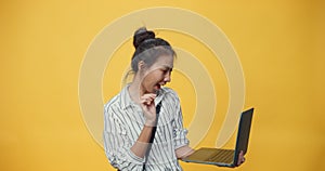 Happy beauty Asia youth casual girl typing laptop computer stand over isolate yellow empty space background looking at camera with