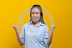 Happy beauty asian young woman showing excite expression.  Shot in studio isolated on yellow background