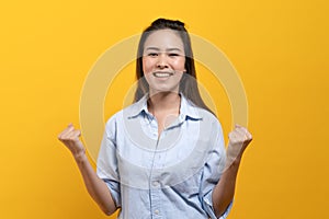 Happy beauty asian young woman showing excite expression.  Shot in studio isolated on yellow background