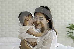 Happy Beauty mother Holding Cute Sweet Adorable Asian Baby wearing white dress smiling and playing