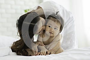 Happy Beauty mother Holding Cute Sweet Adorable Asian Baby wearing white dress smiling and playing with happiness