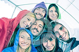 Happy best friends taking selfie wearing hoodies outdoors photo