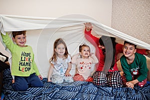 Happy big family is having fun together in bedroom. Large family morning concept. Mother with four kids wear pajamas in bed at
