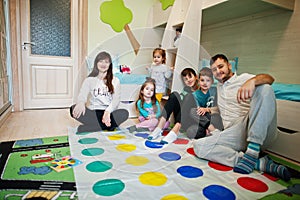 Happy big family having fun together,four kids playing twister game at home