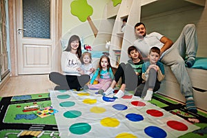 Happy big family having fun together,four kids playing twister game at home