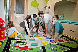 Happy big family having fun together,four kids playing twister game at home