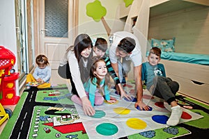 Happy big family having fun together,four kids playing twister game at home